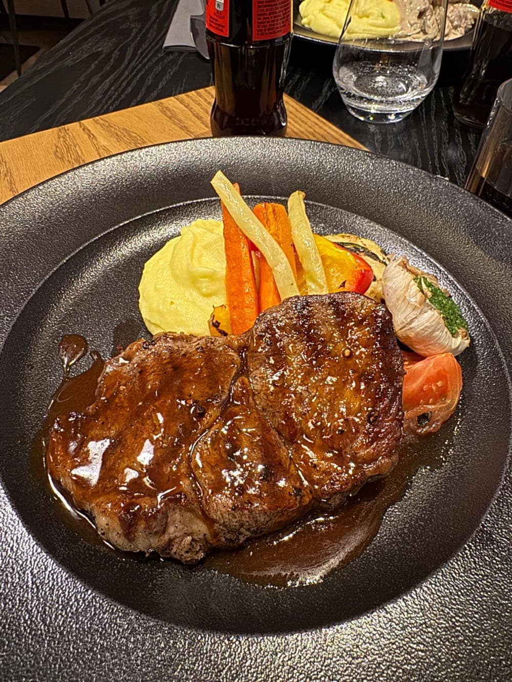 Fotografia real de um bife com puré e legumes, tirada com o telemóvel à mesa